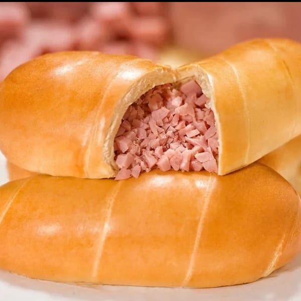 Two golden-brown ham and cheese rolls, one sliced open revealing diced ham filling.